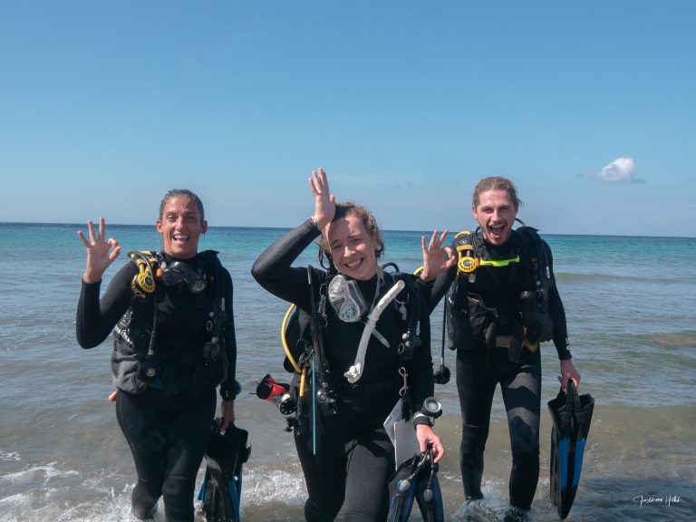 Trois amis plongeurs sortent de l'eau après une plongée passionnante