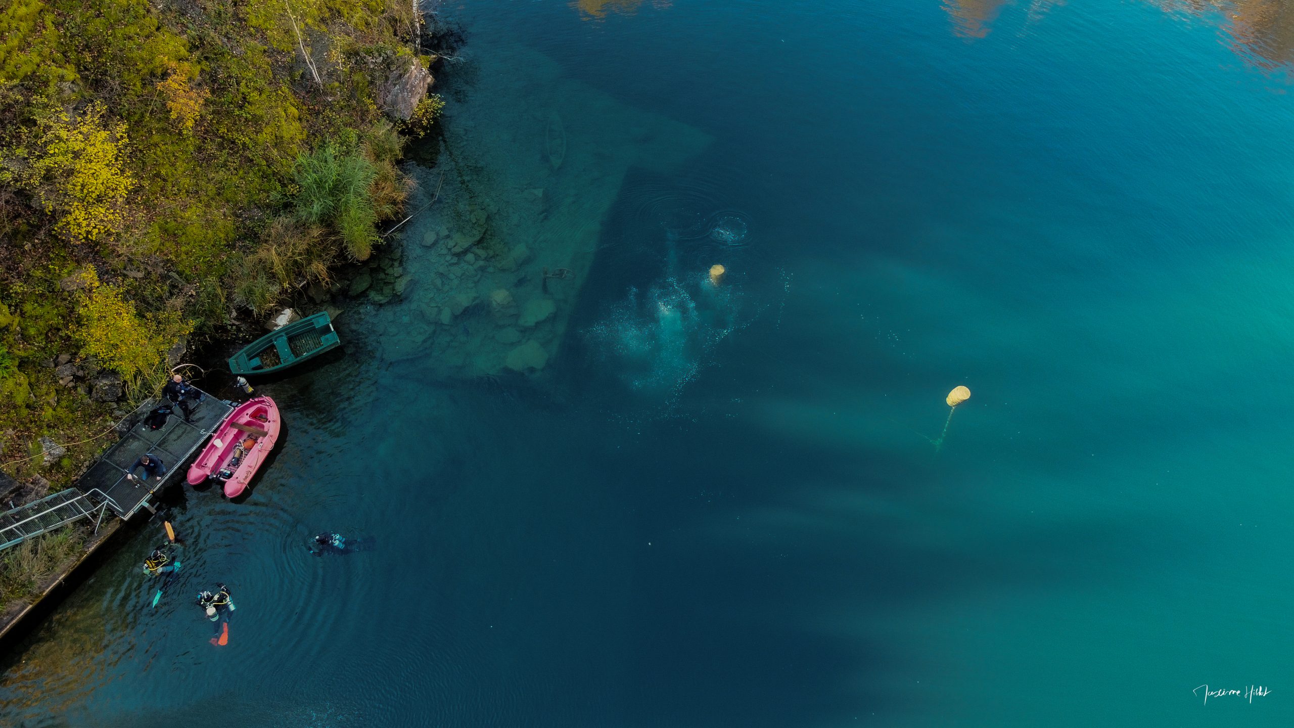 Vue aérienne des eaux cristallines de la carrière de Vodelée en Belgique avec plongeurs, photo par Maxime HIBLOT
