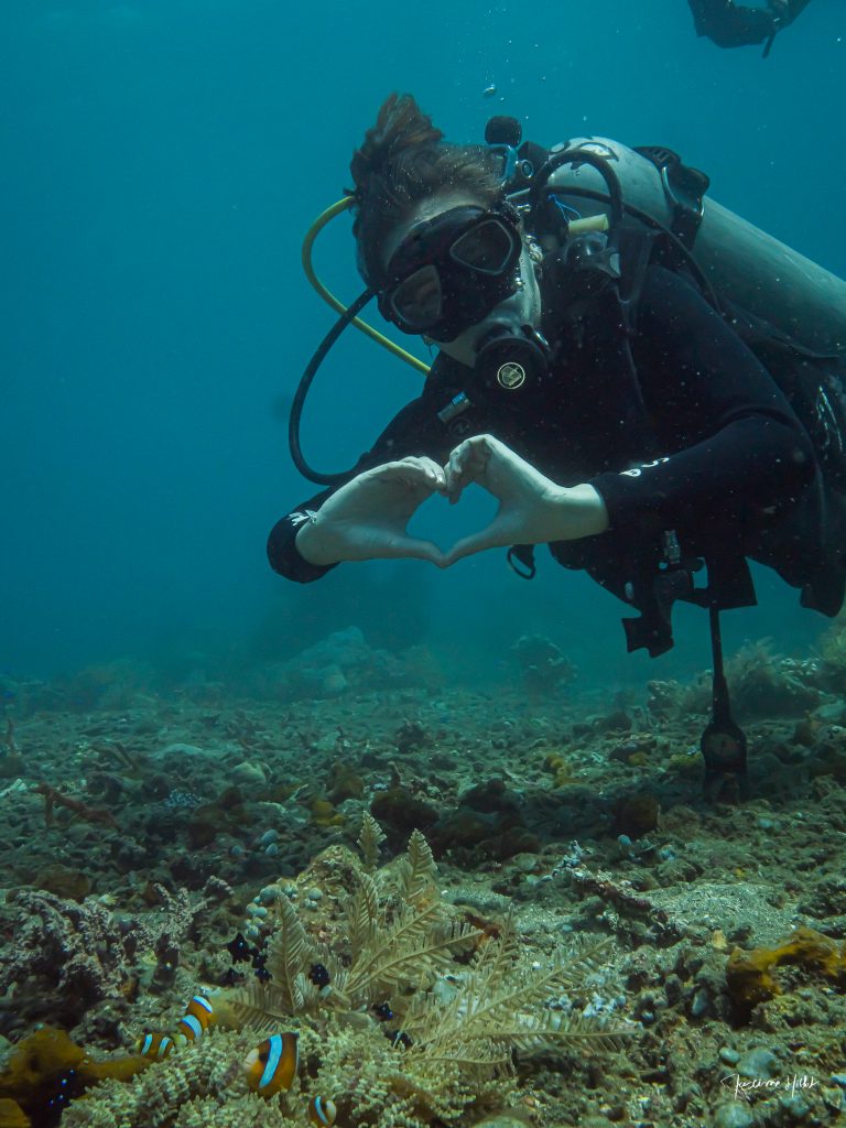 Plongeuse heureuse devant une anémone et ses poissons clown