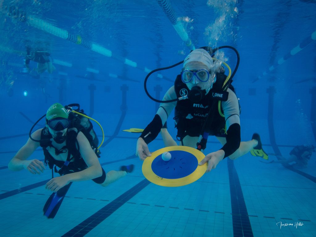 Plongeuse pratiquant un exercice de stabilisation pendant un escape game sous-marin, illustrant la maîtrise des compétences de flottabilité dans un contexte ludique