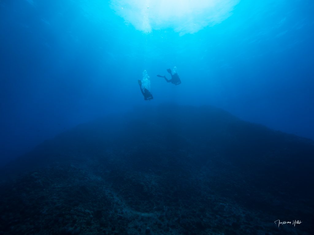 Deux plongeurs explorant les eaux cristallines et profondes de l’île Ronde, un site exceptionnel de plongée à l’île Maurice.