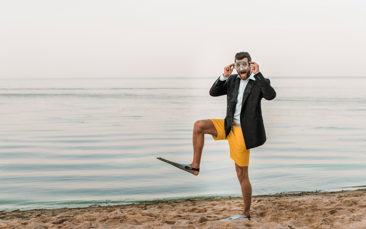 Homme en costume sur la plage portant une paire de palmes